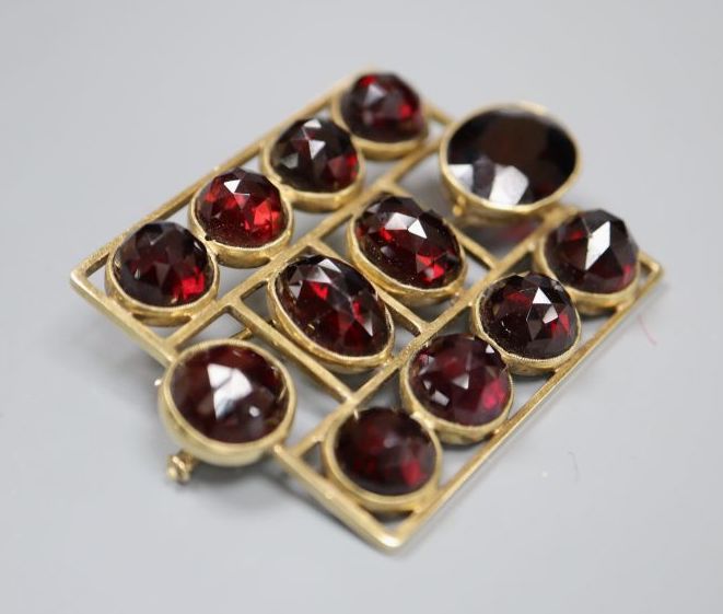 An early 20th century German jugendstil 585 yellow metal and facetted garnet set brooch,